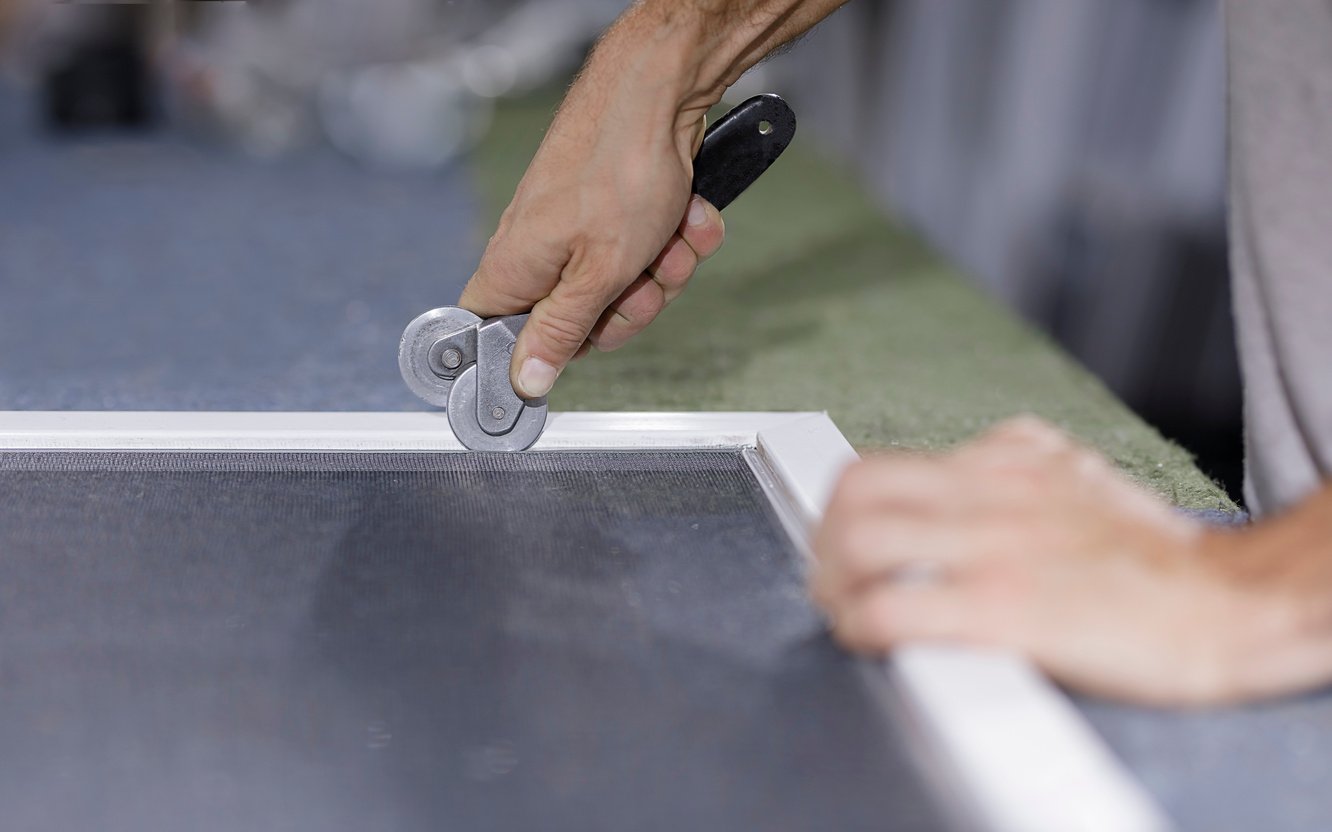 Man putting together a window screen.